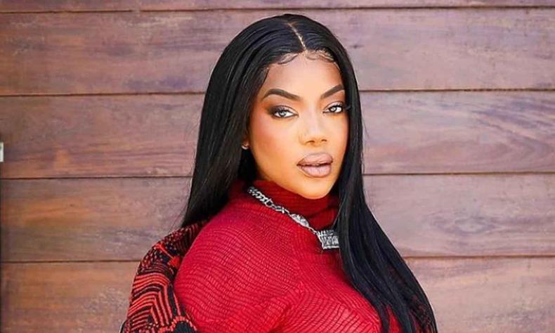 Ludmilla ultrapassou a marca de 2 bilhões de visualizações no Spotify(foto: Reprodução/ Instagram) Ludmilla, usando roupa vermelha e com cabelos lisos soltos, em frente a uma porta de madeira